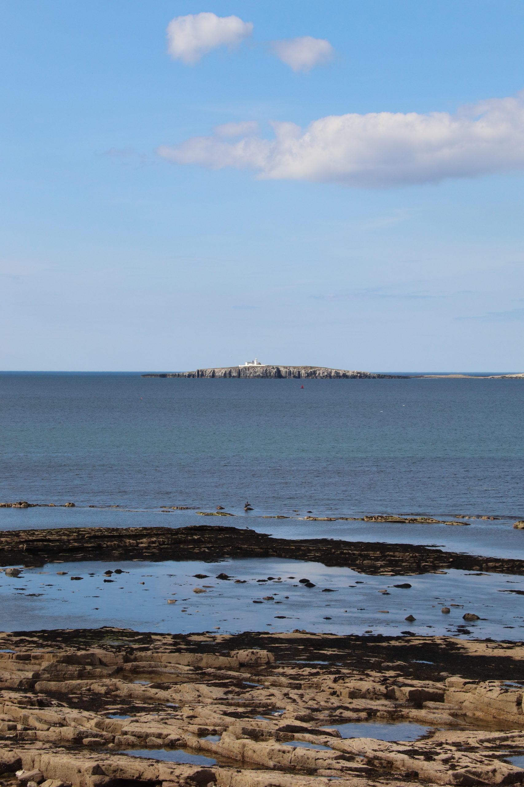 A view of the Farne Islands from Seahouses. There is a white building on the nearest island which is Inner Farne. 